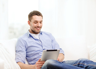 Image showing smiling man working with tablet pc at home