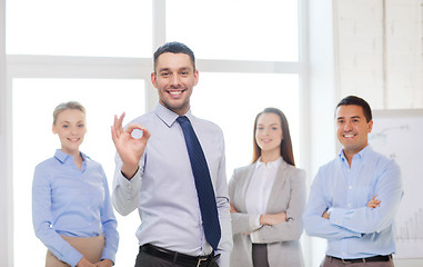 Image showing smiling businessman showing ok-sign in office
