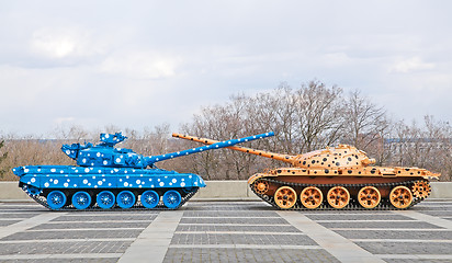 Image showing Brightly colored tanks with crossed barrels.