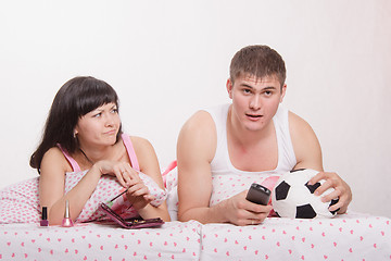 Image showing Skeptical wife looking at her husband football fan