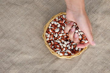 Image showing woman palmful of beans over wicker basket  