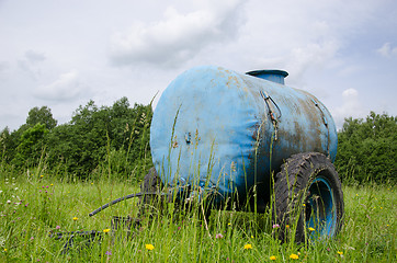 Image showing Blue water cistern drink for farm animal in meadow 