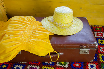 Image showing yellow dress and straw hat lying on old suitcase