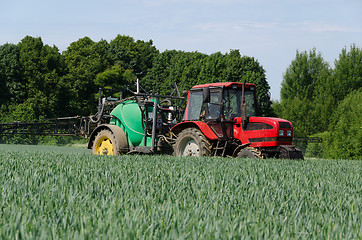 Image showing farm machinery tractor long sprayer work in field 