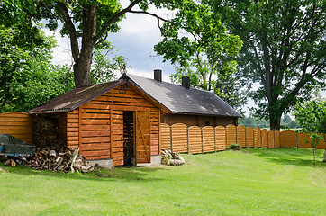 Image showing handmade woodshed in village along wooden fence 