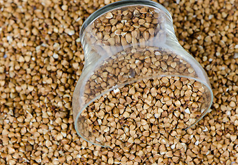 Image showing cup of raw eco buckwheat pile background 