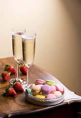 Image showing Two glasses of sparkling wine or champagne with small colorful macaroons