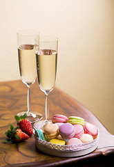 Image showing Two glasses of sparkling wine or champagne with small colorful macaroons