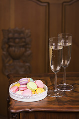 Image showing Two glasses of sparkling wine or champagne with small colorful macaroons