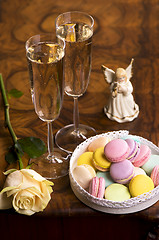 Image showing Two glasses of sparkling wine or champagne with small colorful macaroons