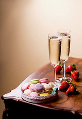 Image showing Two glasses of sparkling wine or champagne with small colorful macaroons