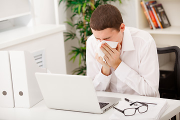 Image showing man sneezing while working