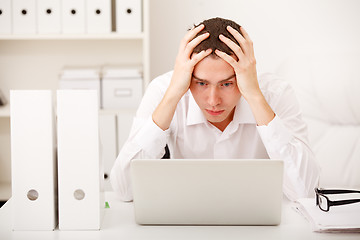 Image showing Despairing businessman sitting at desk