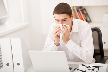 Image showing man sneezing while working