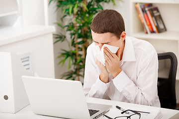 Image showing man sneezing while working