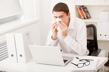 Image showing man sneezing while working