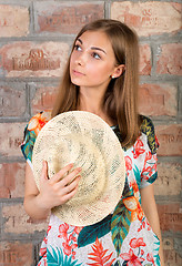 Image showing Portrait of pensive girl with a straw hat in hand.