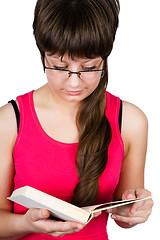 Image showing young beautiful girl with glasses reading a book. isolated