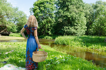 Image showing woman standing with wicker basket in meadow