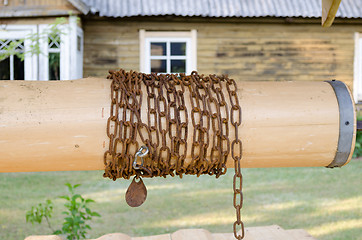 Image showing close up wooden well roller with chain in country  