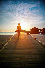 Image showing Silhouette of a girl walking along the pier at sunset