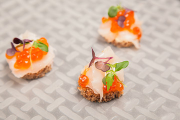 Image showing Salmon eggs, fish, and herbs canapes