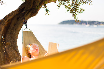 Image showing Lady reading book in hammock.