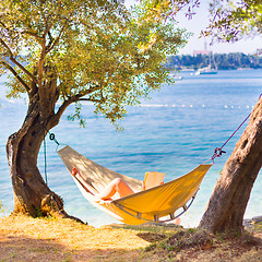 Image showing Lady reading book in hammock.