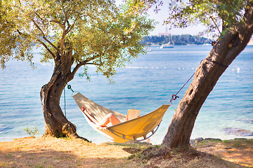 Image showing Lady reading book in hammock.