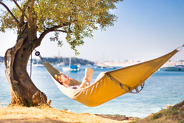 Image showing Lady reading book in hammock.