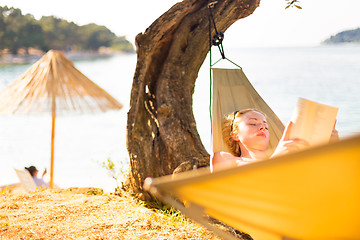 Image showing Lady reading book in hammock.