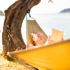 Image showing Lady reading book in hammock.