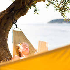 Image showing Lady reading book in hammock.