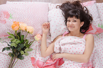 Image showing cute girl in bed surprised bestowed a bouquet of roses