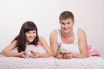 Image showing girl and guy with a wad of dollars in bed