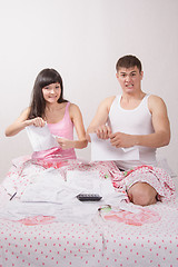 Image showing Newlyweds sitting in bed tearing account for rent