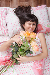 Image showing Beautiful young girl lying in bed with flowers