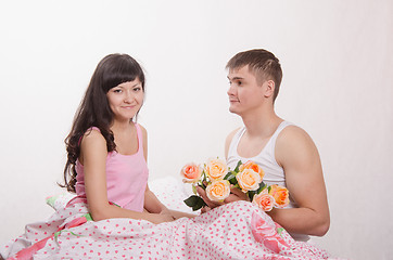 Image showing Girl receives flowers from a guy sitting in bed