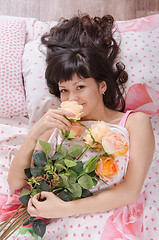 Image showing Girl enjoying fragrance of flowers, lying in bed