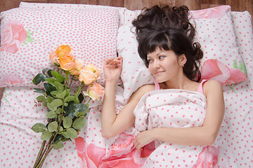 Image showing girl wakes up and enjoys bouquet of flowers donated by