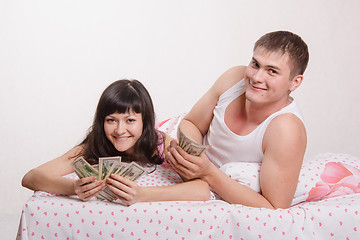 Image showing Happy girl and guy with wad of money in bed