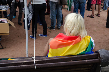 Image showing blonde woman sit on bench dressed rainbow gay flag 