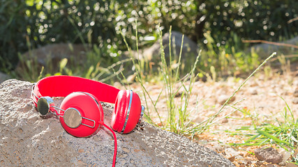 Image showing Bright red wired headphones on the rock