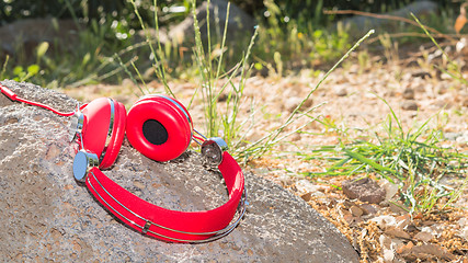 Image showing Vivid red wired headphones on the stone