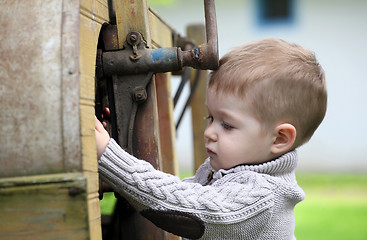 Image showing 2 years old curious Baby boy managing with old agricultural Mach