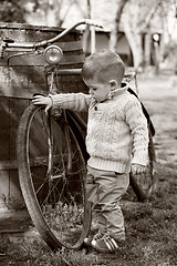 Image showing 2 years old curious Baby boy walking around the old bike