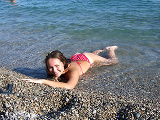 Image showing The sexual girl lays on a pebble on seacoast