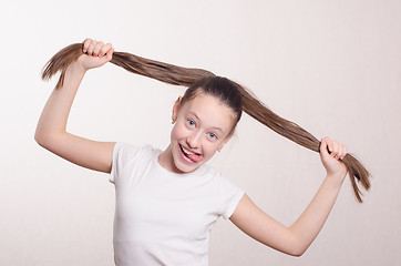 Image showing Twelve year old girl holding hair and tongue out