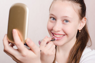 Image showing Teen girl paints lips with lipstick