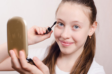 Image showing Happy teen girl paints eyelashes